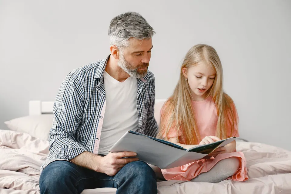 Een vader en zijn dochter lezen samen een boek op bed